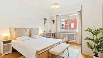 Een moderne slaapkamer met een houten bed, nachtkastjes, een bureau en een potplant.