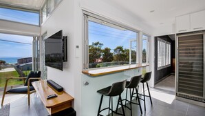 Eine moderne Küche mit großem Fenster, einer Bar mit Hockern und einem an der Wand befestigten Flachbildfernseher.