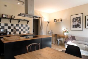 A modern kitchen with a central island, a dining area, and a living space with a sofa and a coffee table.