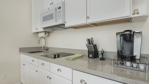 A kitchen with white cabinets, a built-in microwave, a coffee maker, and a knife block.