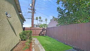 A residential backyard with a wooden fence, a concrete pathway, and a well-maintained lawn.