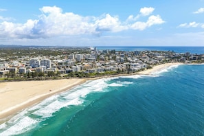Un paysage urbain côtier avec une plage, des immeubles de grande hauteur et un ciel dégagé.