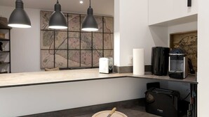 A modern kitchen with three pendant lights, a Bosch toaster, a coffee maker, and a map artwork on the wall. - Stylish Sevre I Chic 1-BR in the Heart of the 6th (Paris)