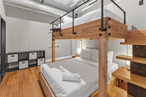 Een stapelbed met houten frame en metalen spijlen, een nachtkastje, en een opbergunit met lades.