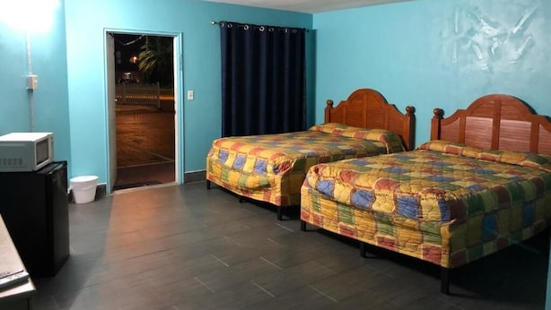 A room with two beds, a microwave, a small table, and a door leading outside.