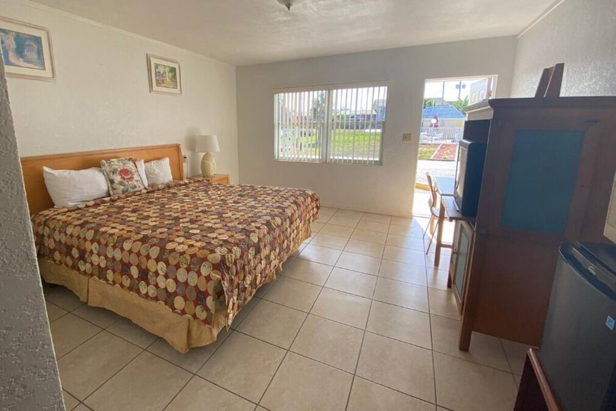 Quarto com cama, escrivaninha, cadeira, janela e porta.