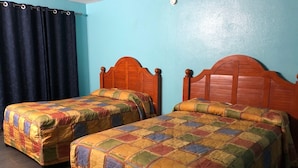 Two single beds with wooden headboards in a room with teal walls and a dark curtain.