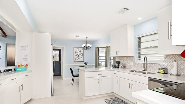 A modern kitchen with white cabinets, a central island, and a dining area with a chandelier. - Family Ready Spacious Retreat - 4BR, Sleeps 8, Pet Friendly with Gazebo (Houston)