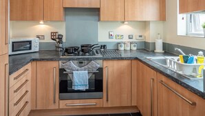 Eine moderne Küche mit Holzausstattung, einem Backofen, einer Mikrowelle und einem Spülbecken mit diversen Küchenutensilien.