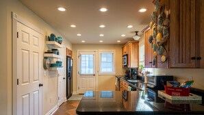 A kitchen with wooden cabinets, a black countertop, and a refrigerator.