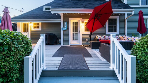 A house with a covered porch, a red umbrella, and outdoor seating.