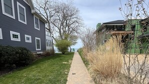 A paved pathway leading to a house with a grey exterior and white trim. - Haven Hideaway by Cottages on Wash is the perfect vacation home! (South Haven)