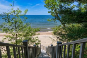 A wooden staircase leading to a beach with a view of the ocean. - Gebhard Chalet - Charming, private, beachfront chalet nestled in a wooded dune on Lake Michigan (Covert)