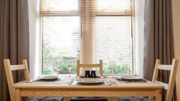 A dining table with four chairs, set for four people, positioned in front of a window with blinds. - ☆ Quiet Ground Floor Apartment Near University ☆ (Dundee)