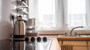 A modern kitchen with a built-in stove, a sink, and a window with sheer curtains. - ☆ Quiet Ground Floor Apartment Near University ☆ (Dundee)