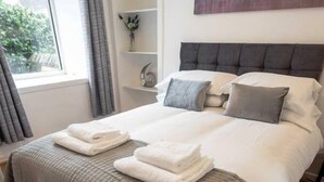 A neatly made bed with a grey quilt, two pillows, and folded towels. - ☆ Quiet Ground Floor Apartment Near University ☆ (Dundee)