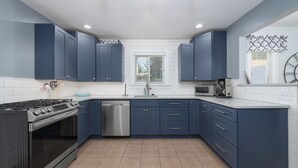 Uma cozinha moderna com armários azul escuro, fogão de aço inoxidável e lava-louças.