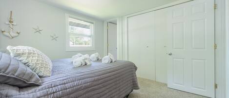 Une chambre à coucher avec un lit, une fenêtre, une armoire et des éléments décoratifs sur les murs.