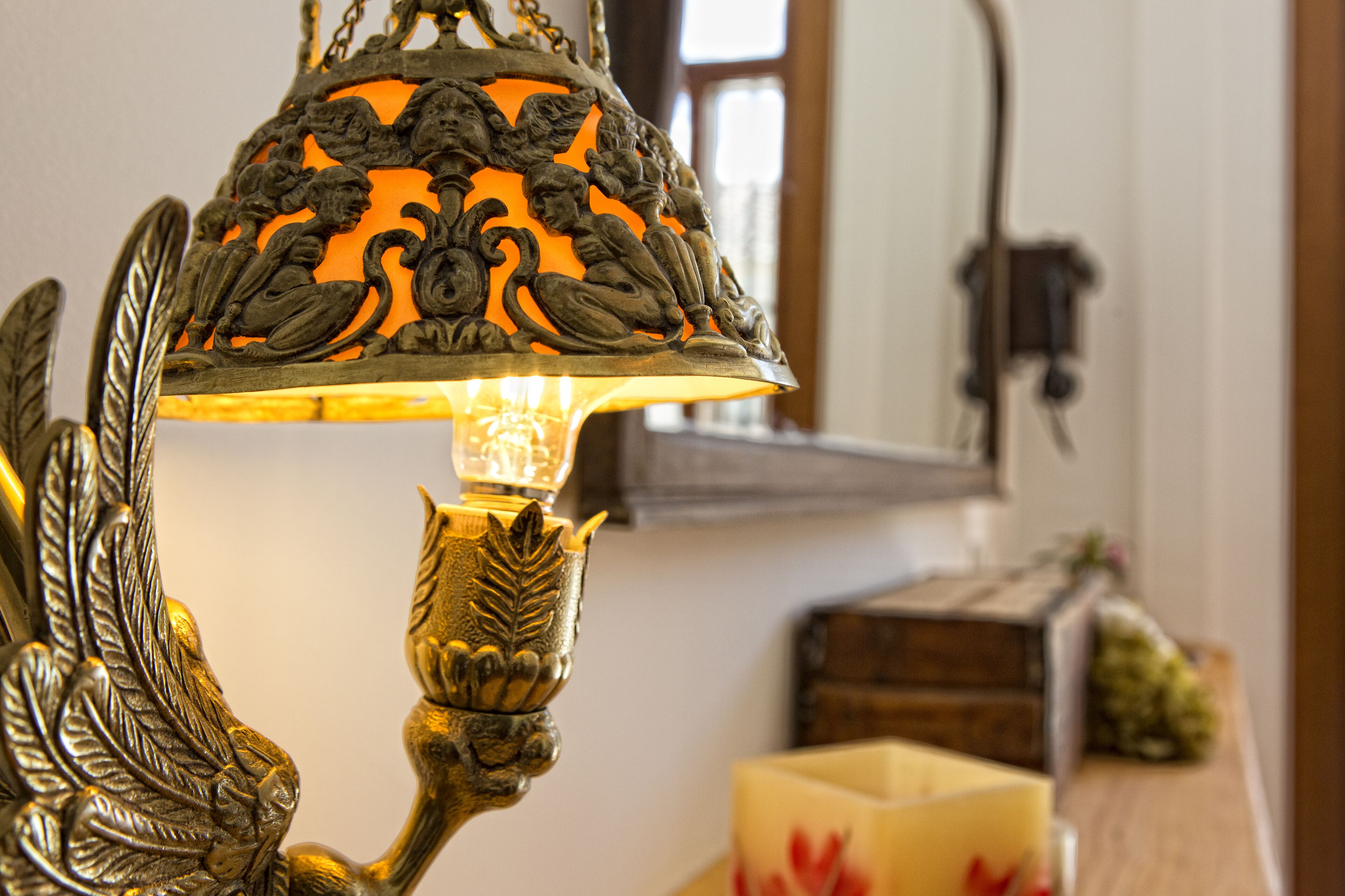 Een decoratieve messing lamp met ingewikkelde versieringen en een gloeiende lamp.