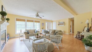 A spacious living room with a fireplace, two sofas, a coffee table, and a ceiling fan.