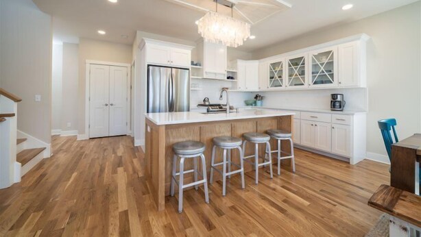 A modern kitchen with a central island, bar stools, white cabinetry, and a chandelier. - Beach Breeze - 5 bedroom 4.5 bath vacation rental located just a block from the beach! (South Haven)