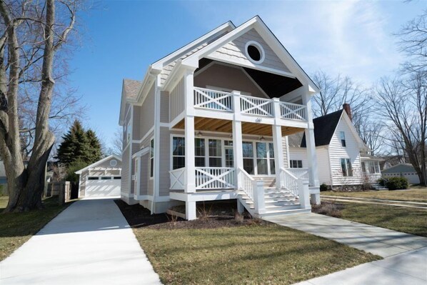 A two-story house with a balcony on the upper floor, a front porch, and a garage.