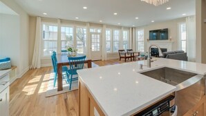 A spacious kitchen with a large island, a dining area with blue chairs, and a fireplace. - Beach Breeze - 5 bedroom 4.5 bath vacation rental located just a block from the beach! (South Haven)