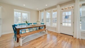 A dining area with a wooden table, blue chairs, and a bench. - Beach Breeze - 5 bedroom 4.5 bath vacation rental located just a block from the beach! (South Haven)