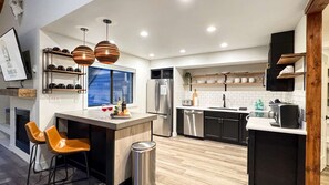 A modern kitchen with a central island, stainless steel appliances, and pendant lighting.
