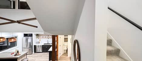 Eine moderne Küche mit Edelstahlgeräten, eine Essecke mit Barhocker und eine Treppe, die in eine andere Ebene führt.