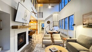 A spacious living area with a fireplace, a dining table, and comfortable seating.