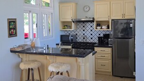 A kitchen with a central island, a stove, a refrigerator, and a microwave. There are two stools at the island. - A entire beach house in front of the Pacific  for nature-loving families! (San Lorenzo)