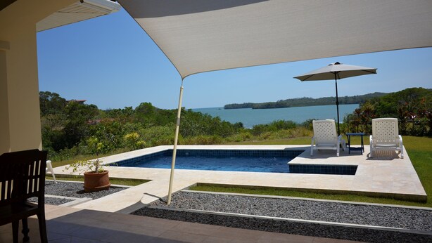 A pool area with a view of the sea, surrounded by greenery and furnished with chairs and a table. - A entire beach house in front of the Pacific  for nature-loving families! (San Lorenzo)