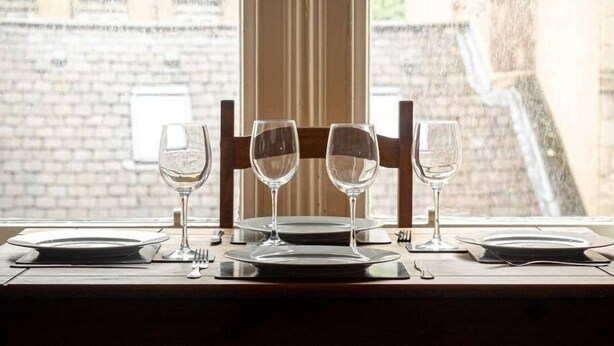 A table set for four with wine glasses and plates, positioned by a window overlooking a brick building. - ☆ Central, Spacious Apartment Close to University☆ (Dundee)