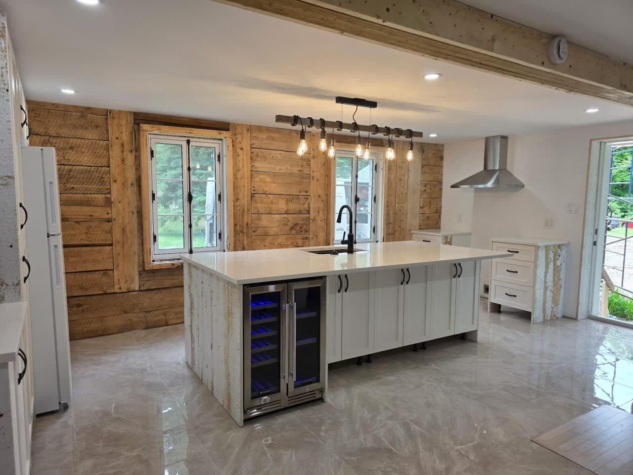 A modern kitchen with wooden walls, a central island, built-in appliances, and a large window.