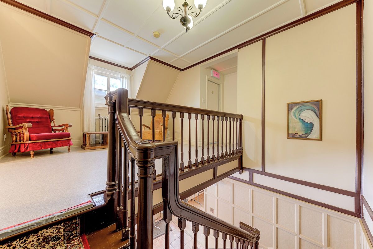 A staircase with a wooden handrail and balusters, leading to an upper floor.