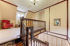 A staircase with a wooden handrail and balusters, leading to an upper floor.