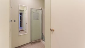 A hallway with a door leading to a room, a mirror, and a glass shower door. - Villa st-Léon (Saint-Gabriel-de-Valcartier)