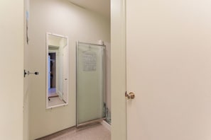 A hallway with a door leading to a room, a mirror, and a glass shower door. - Villa st-Léon (Saint-Gabriel-de-Valcartier)