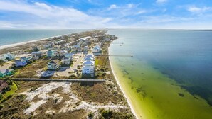 An aerial view of a coastal residential area with houses, a beach, and a pier extending into the water. - 21st Floor Penthouse | Portofino Tower 4 (Pensacola Beach)
