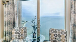 A balcony with a view of the sea, two patterned chairs, a glass table, and a vase with branches. - 21st Floor Penthouse | Portofino Tower 4 (Pensacola Beach)