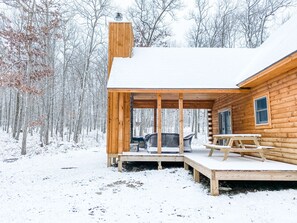 A wooden cabin with a covered porch and a dining table. - Modern Cabin with Hot Tub and Outdoor Fireplace! (McHenry)