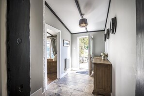 A hallway with a dark door, a wooden cabinet, and a hanging light fixture. - Barn Conversion - Hot Tub - Penally - Tenby (Tenby)