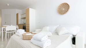 Une chambre d’hôtel moderne avec un lit bien fait, un coin repas et une kitchenette.