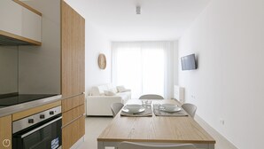 Une cuisine moderne avec des meubles en bois, un four encastré et un coin repas doté d’une table en bois, mise pour quatre personnes.