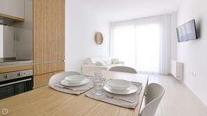 Une cuisine moderne dotée d’un four encastré et d’un coin repas avec une table en bois, mise pour deux personnes.