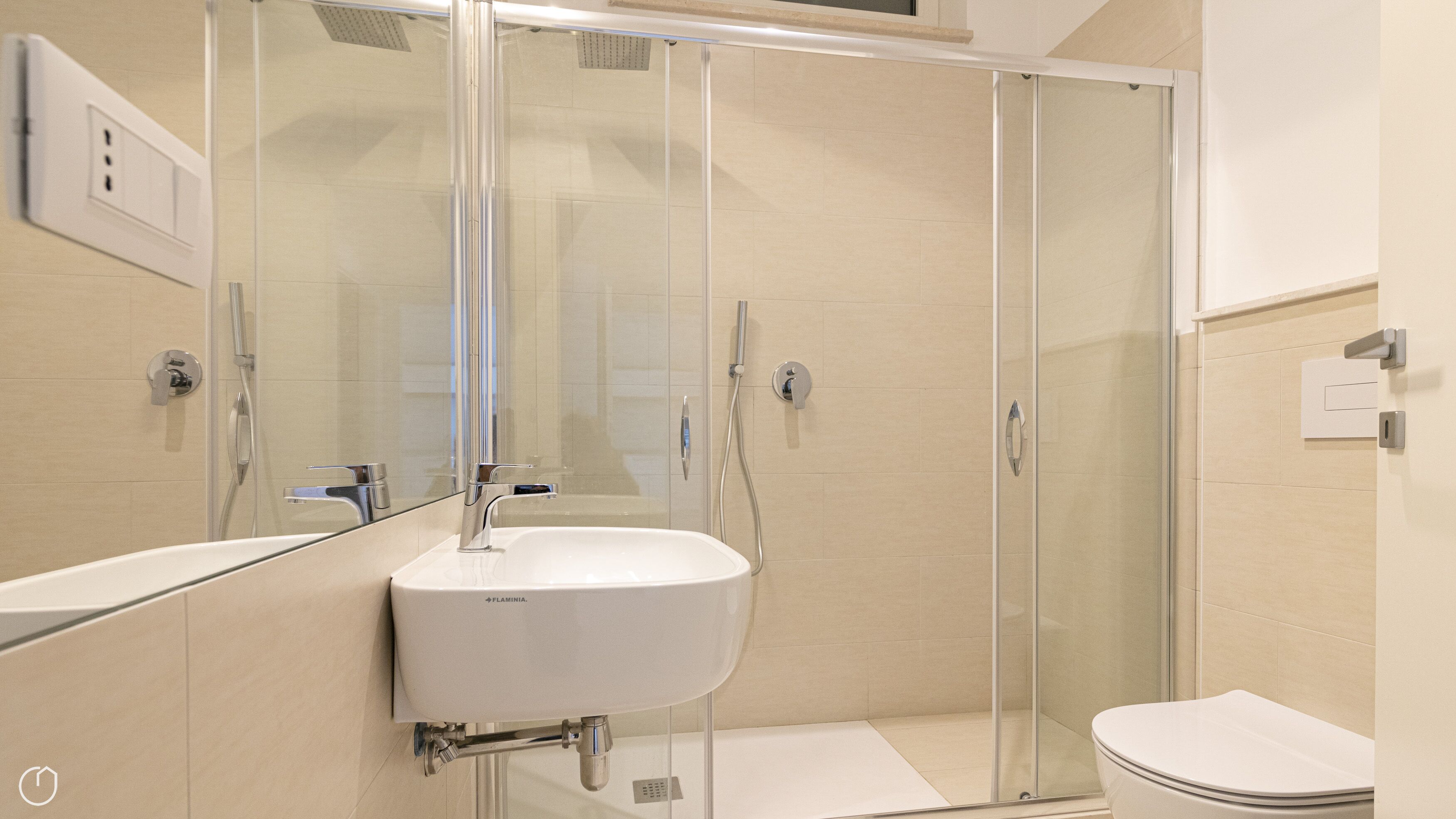 Een moderne badkamer met een douchecabine van glas, een wit wastafelmeubel en een toilet.