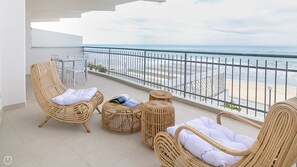 A balcony with wicker furniture, including two chairs and two ottomans, overlooking a beach with a metal railing. - Rivazzurra Homes - 7 (Termoli)