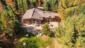 Eine Lodge mit einer großen Terrasse, einer überdachten Veranda und einer Mauer aus Natursteinen.