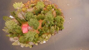 Vista aérea de una pequeña isla con vegetación densa y un edificio de techo rojo.